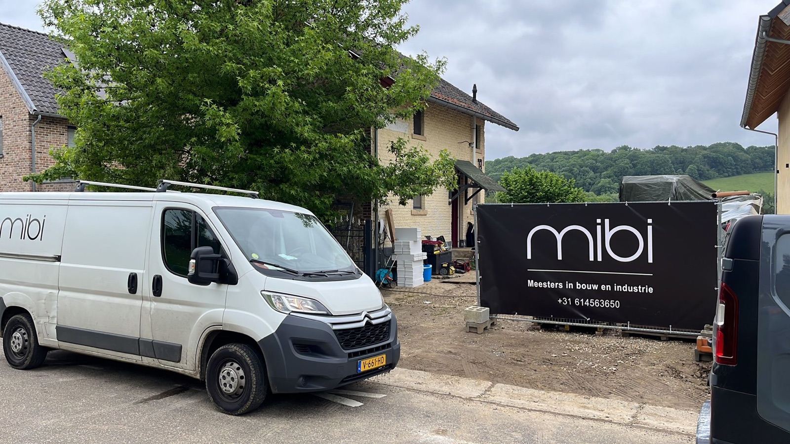Een MIBI-bus en bouwbanner van Meestersinbouw op een bouwproject in Limburg, Nederland